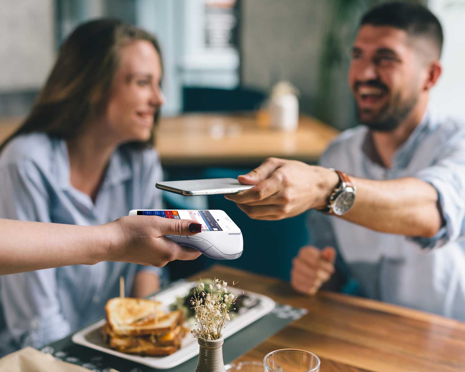 man sits at bar and pays tab with his credit card by tapping