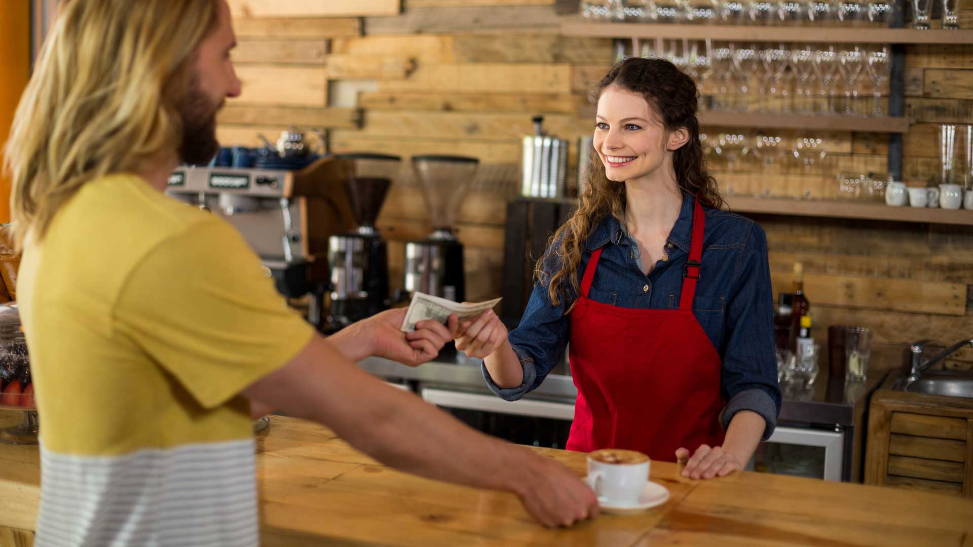 smiling woman giving change back in a coffee shop | cash discount program