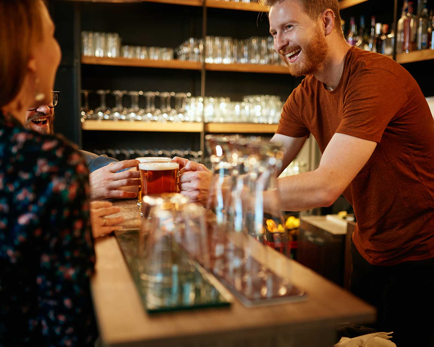man serving two beers to people at a bar | bar tab mangement
