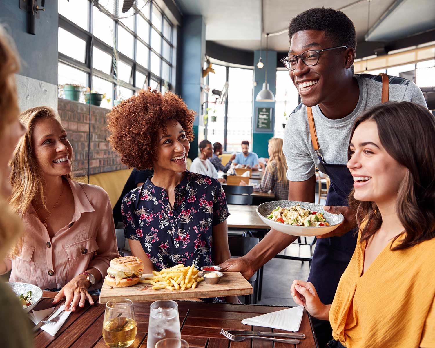 group of friends getting theor meal served to them by a smiling worker | gift and loyalty programs