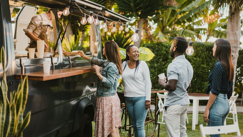 people standing in line to get their food from a van food truck 