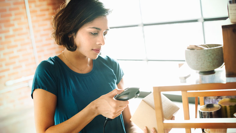 women standing at a desk looking at packages and a computer | Request a Retail POS Demo 